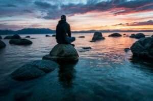 Man sitting on rocks looking out to the ocean